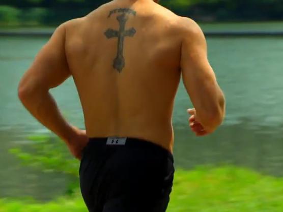 On his back, between his shoulder blades, is a giant cross with the word 