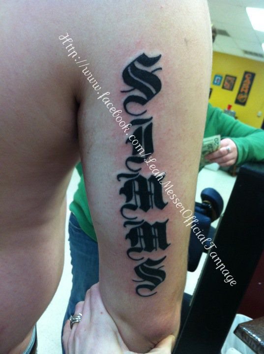  tattoo of the family name SIMMS tattooed down the back of one arm